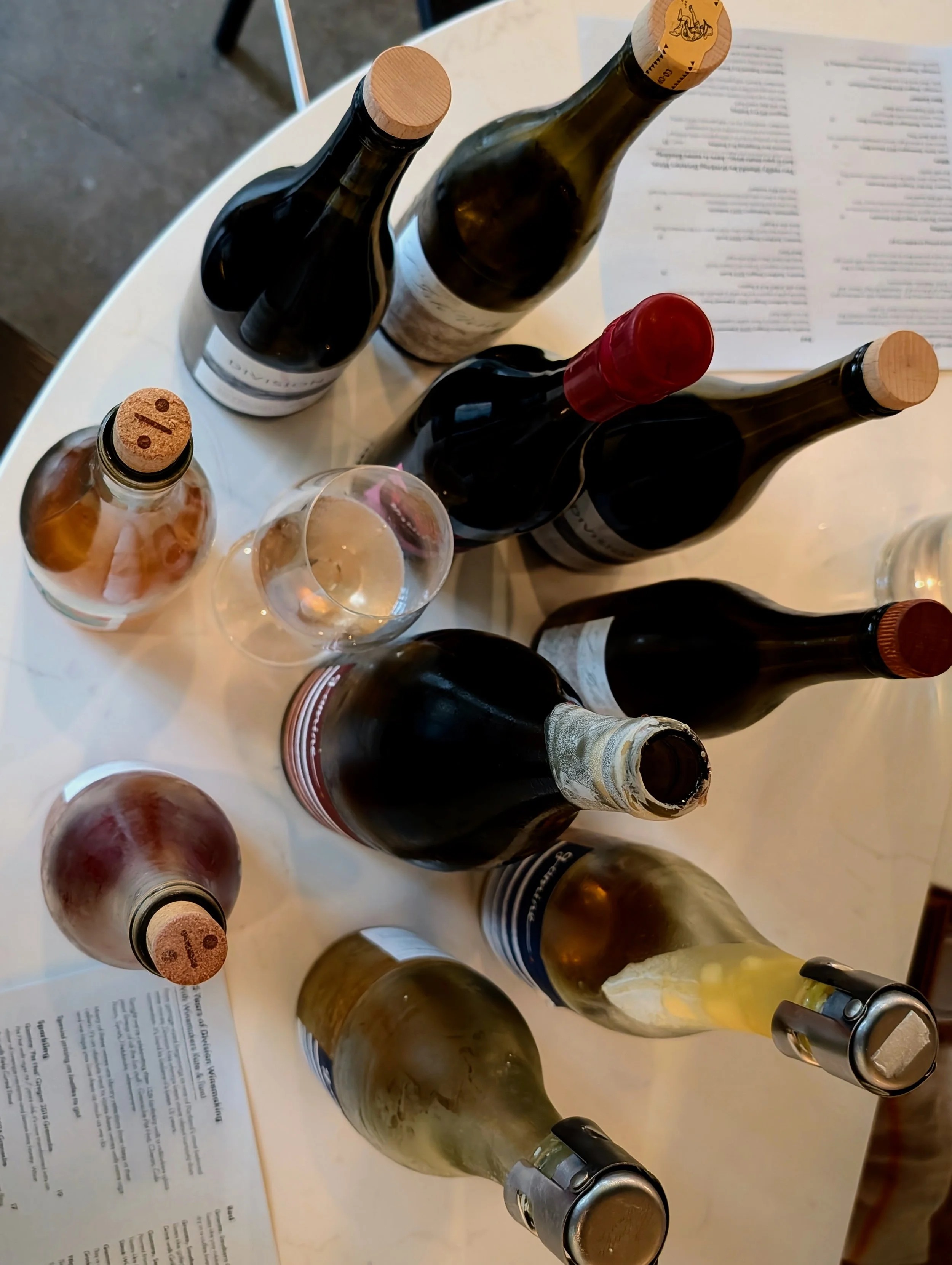 Several bottles of wine and a glass of white wine on a table with menus.