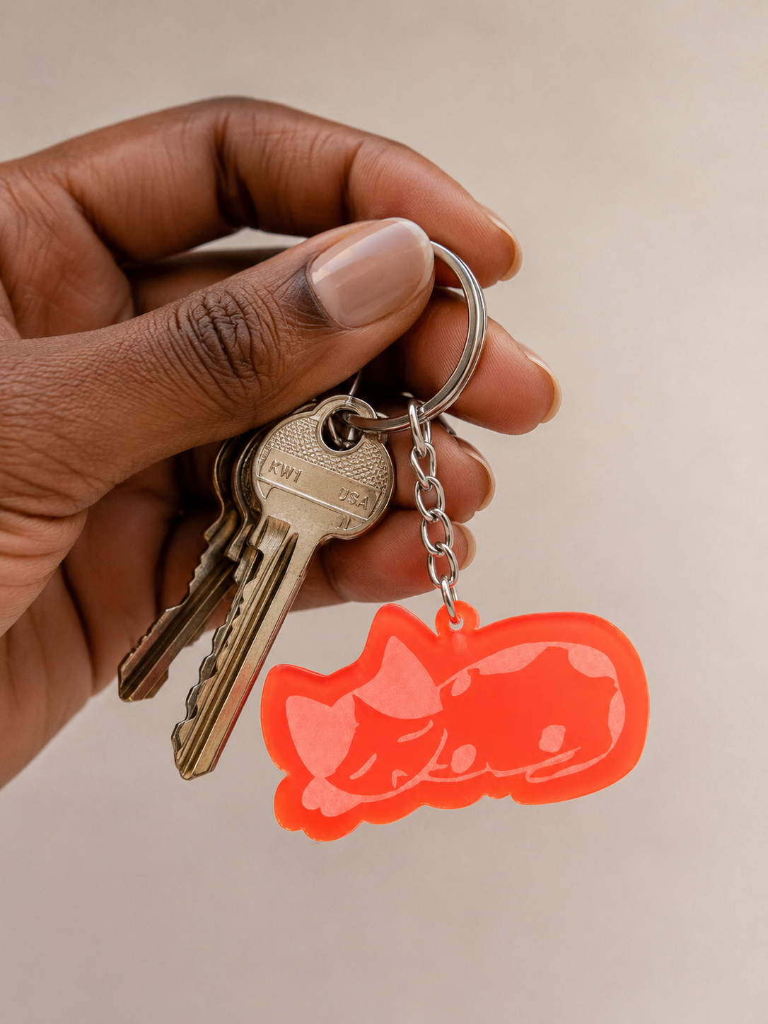 Coral acrylic keychain featuring an illustration of a sleeping cat