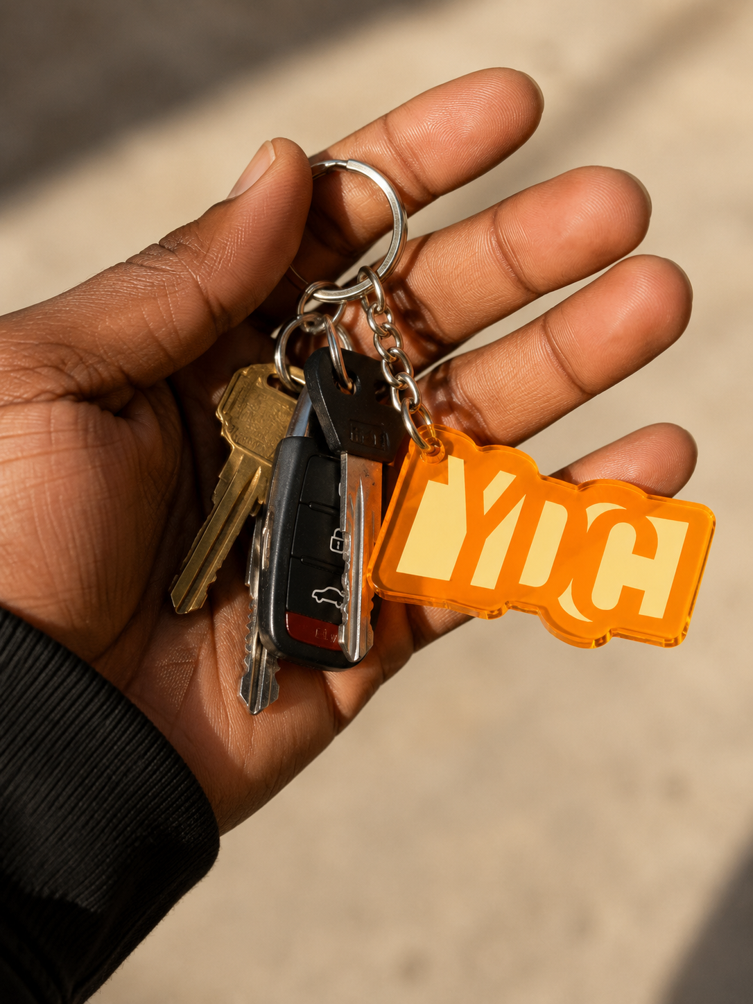 Orange acrylic Youth Design Center logo keychain with silver key ring