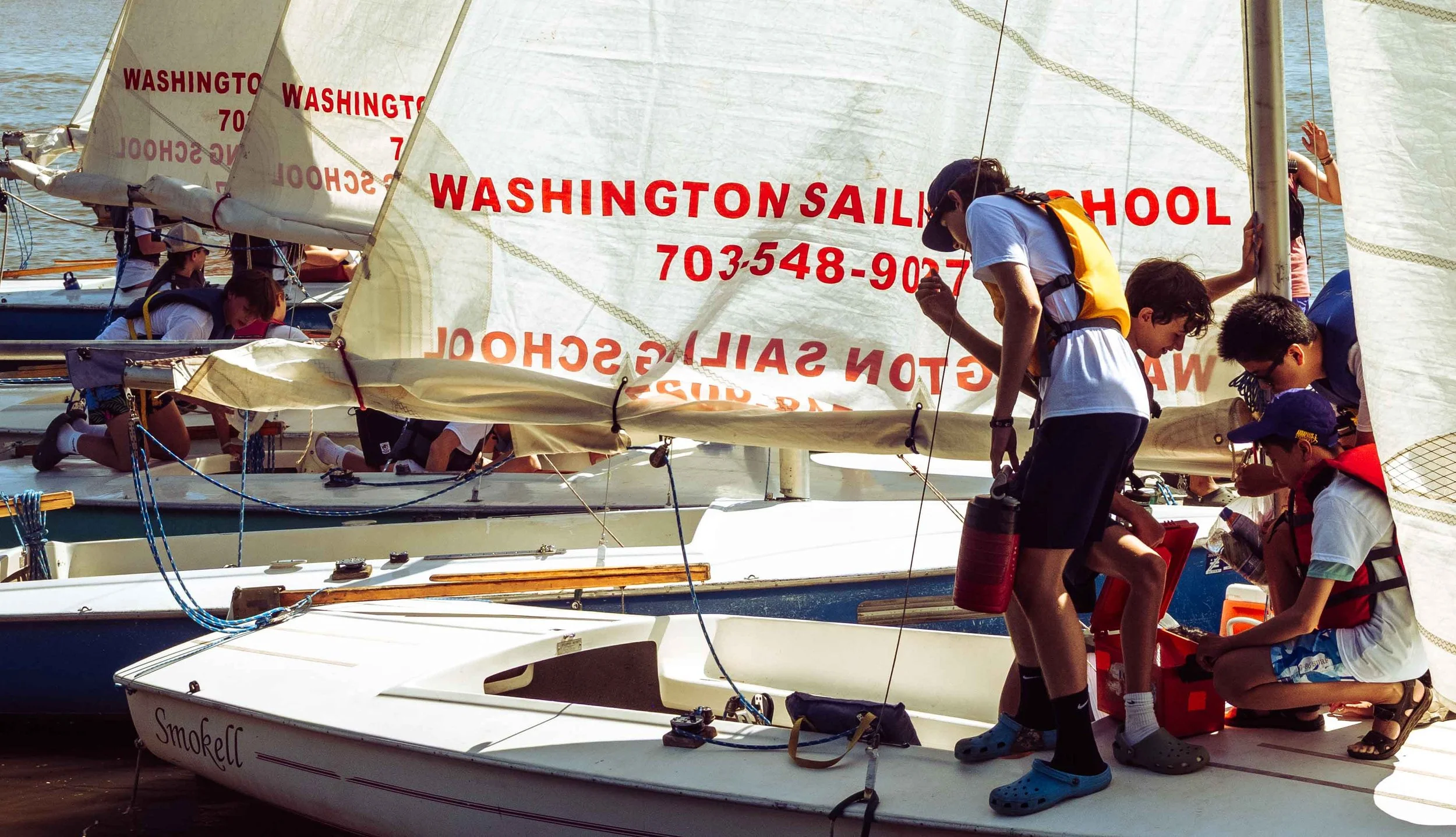 Instructors and students work together to rig sails and inspect equipment prior to a lesson.
