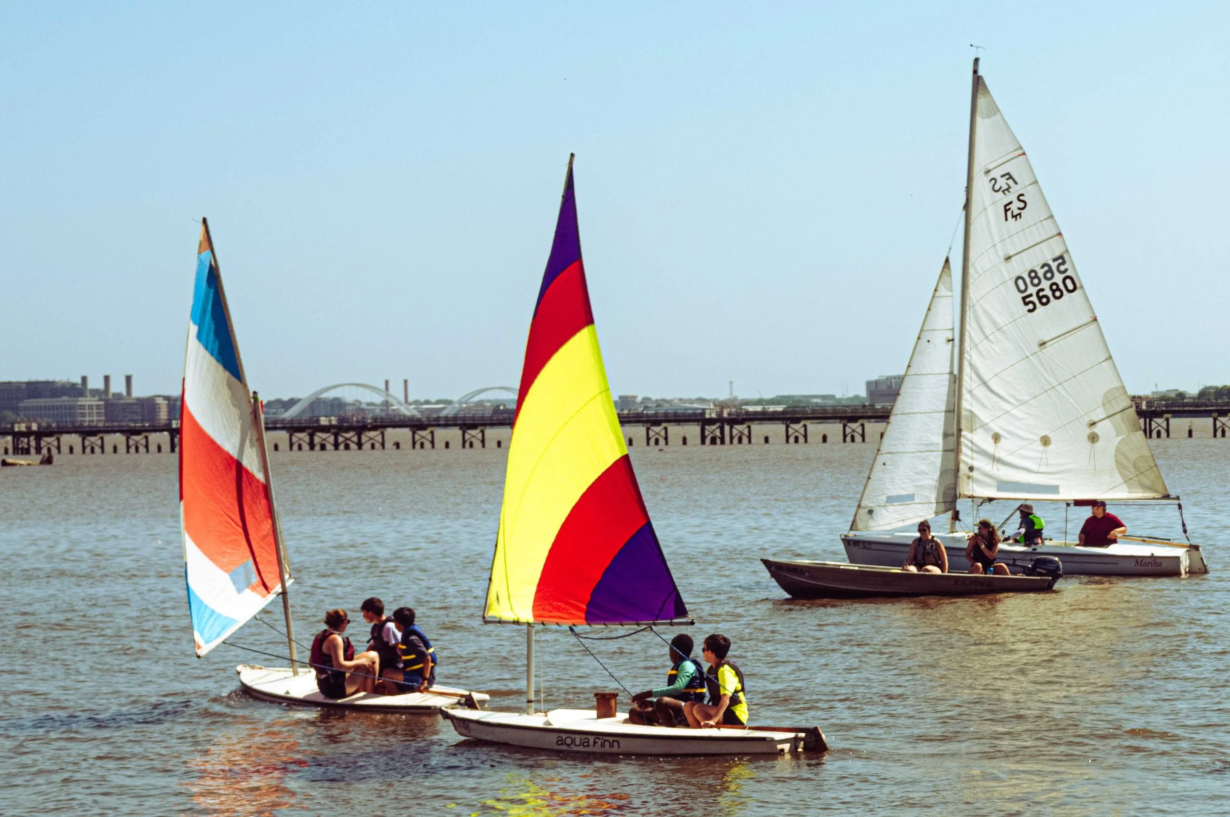 A small fleet of student sailors crosses the Potomac River under steady afternoon winds.