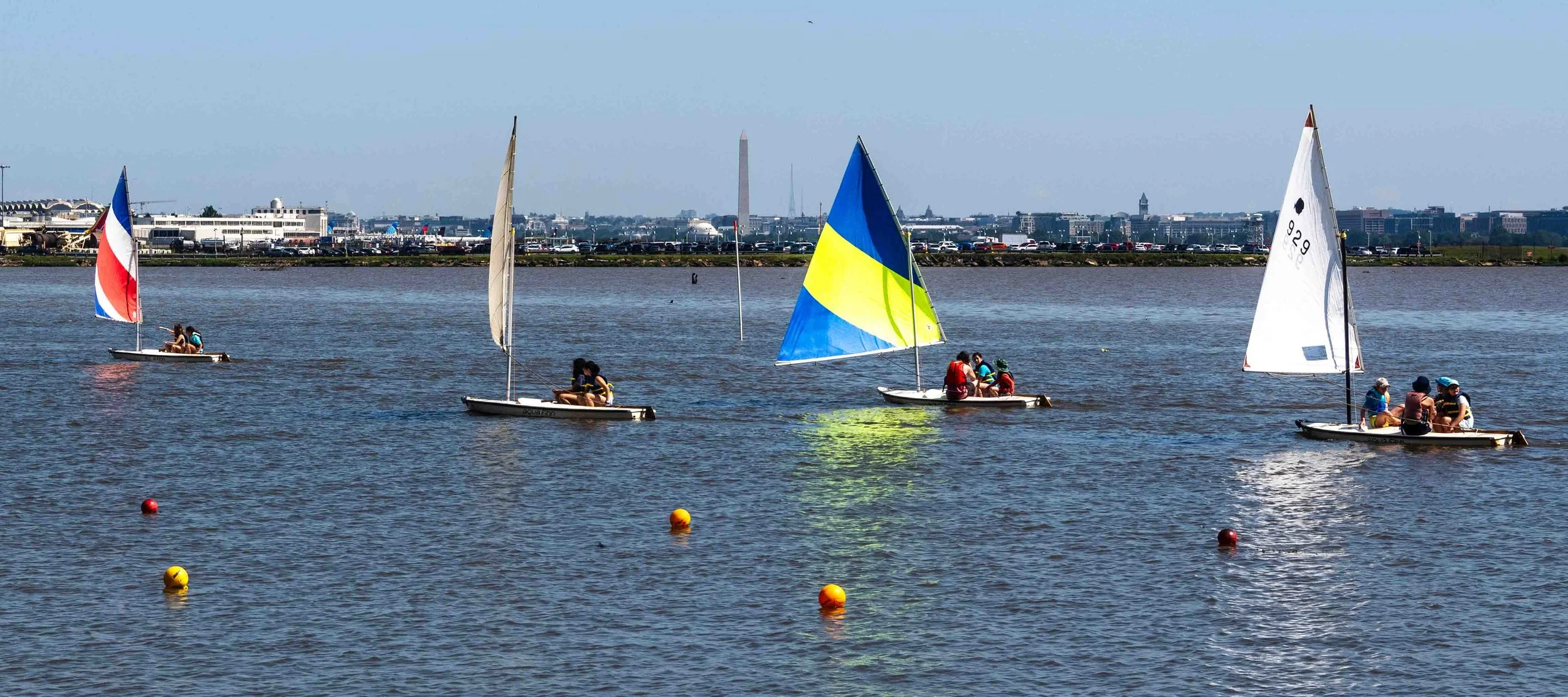 Youth sailors practice sail trim and steering in open water near the Washington shoreline.
