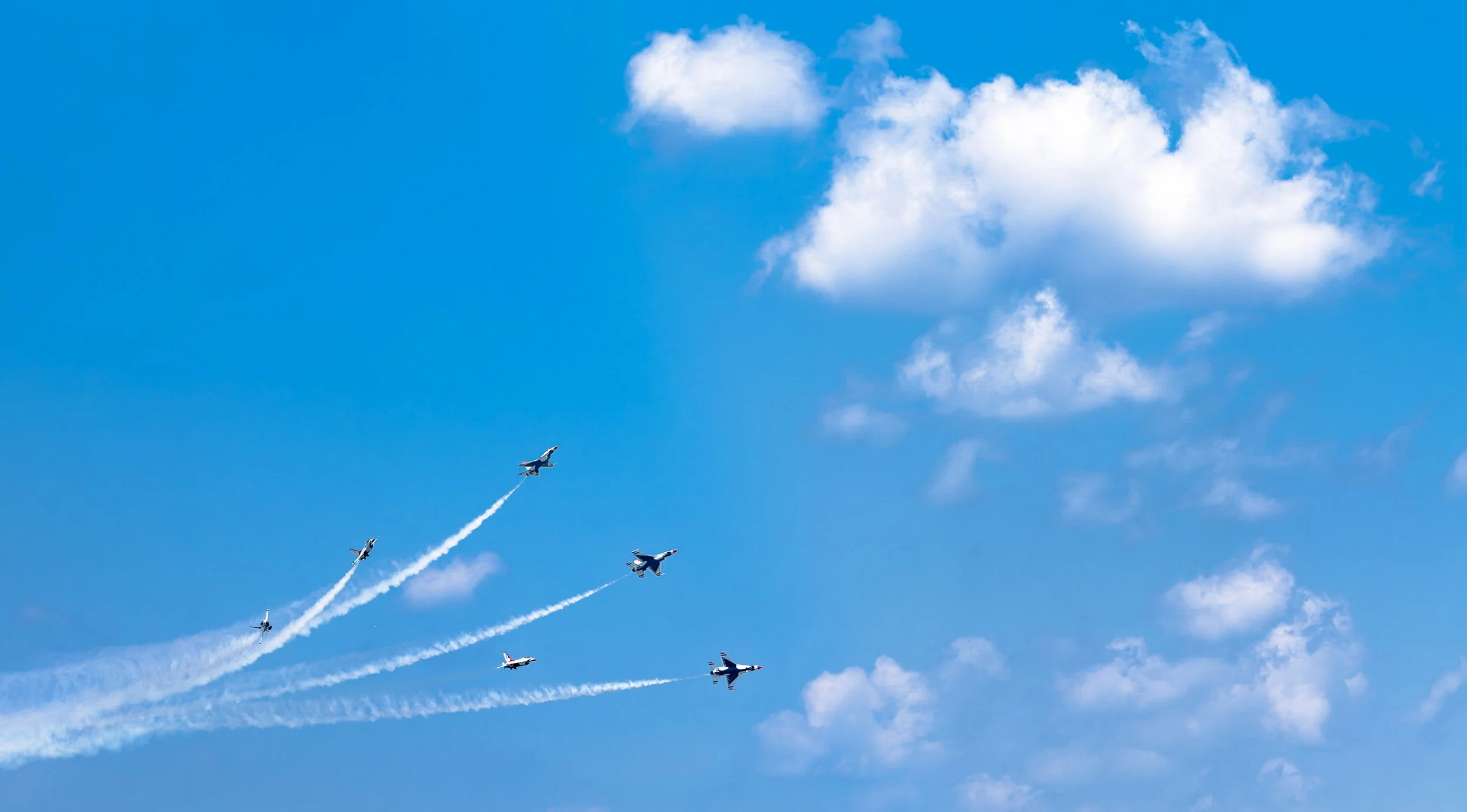 The U.S. Navy Blue Angels perform a dynamic aerial maneuver with sweeping smoke trails over Washington during the America 250 celebration.