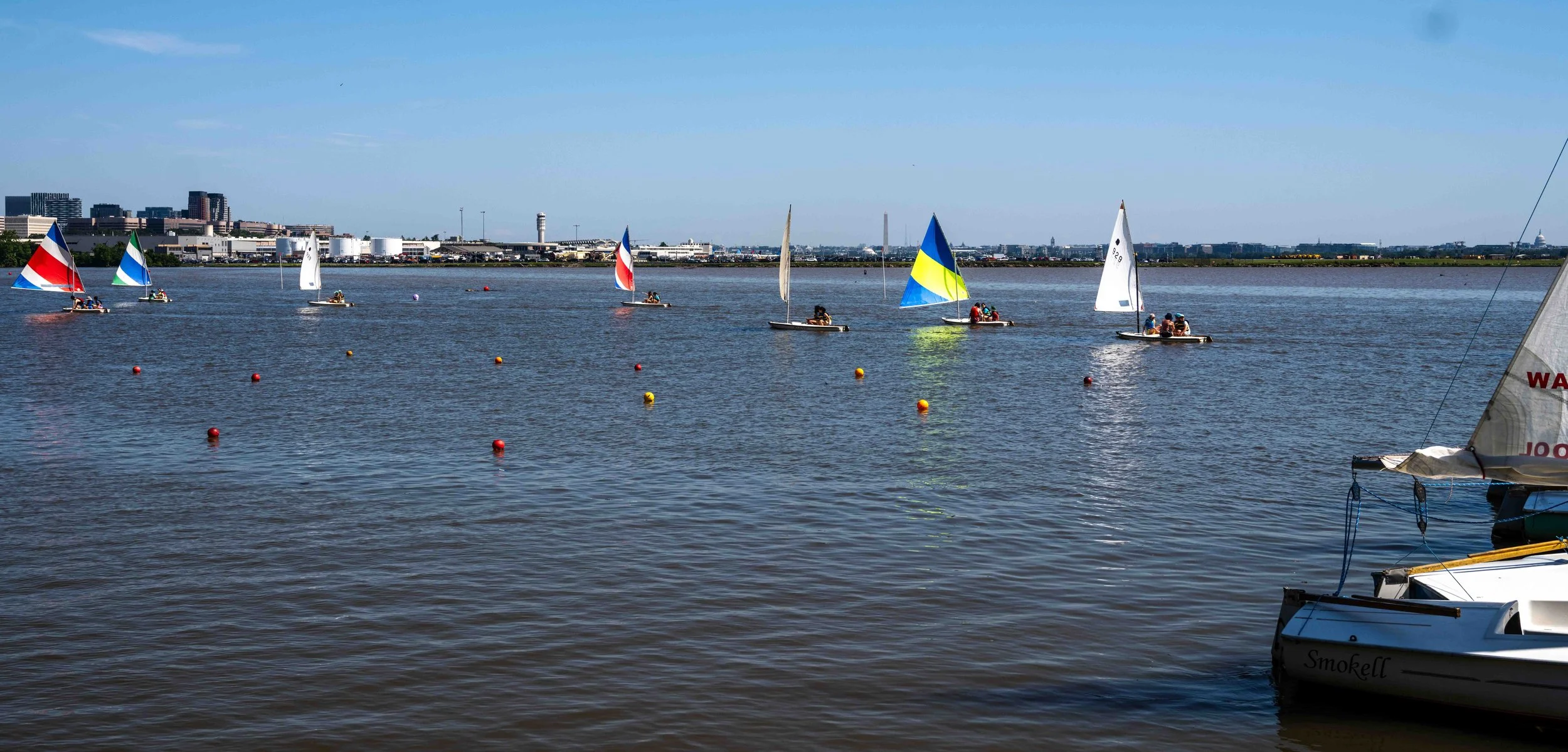 Sailors maneuver through training buoys while learning boat control and navigation techniques.