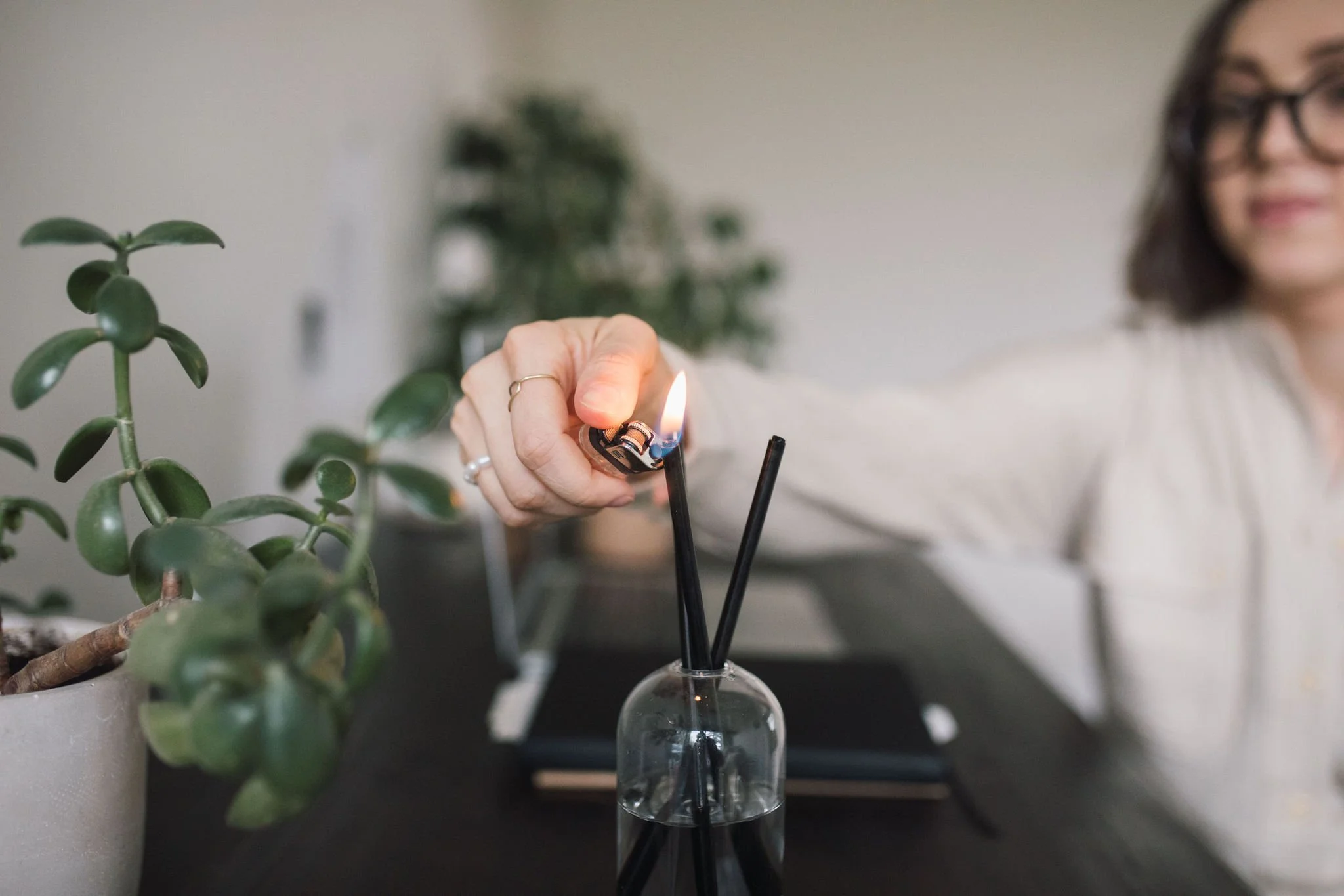 Person lighting a candle during a somatic wellness workshop, symbolizing reflection and setting intentions in the Explore package of Growing with the Seasons series.