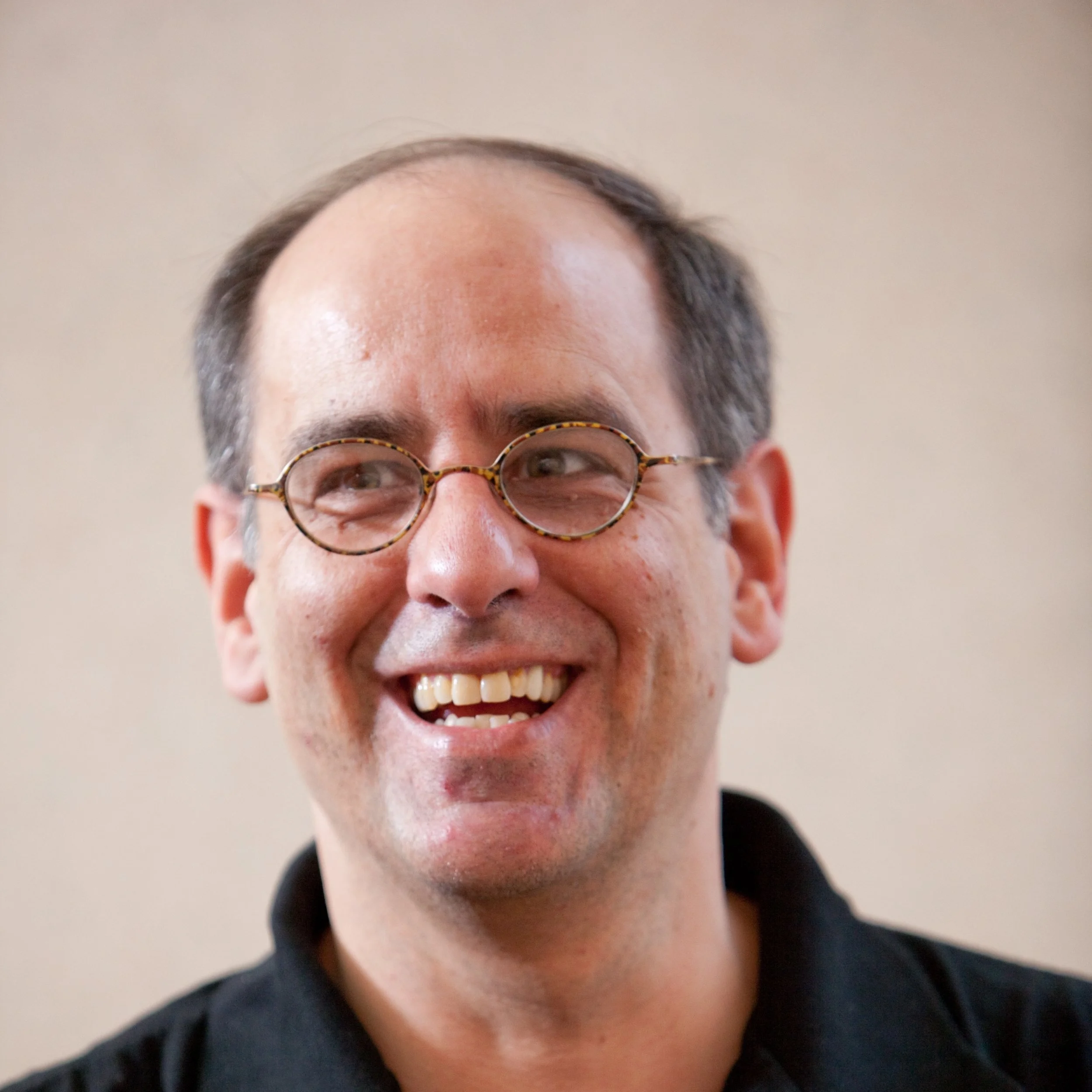 Scott Fraser. Man with glasses smiling, wearing a black shirt