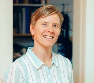 Fritha Pengelly. Person smiling indoors wearing a striped shirt
