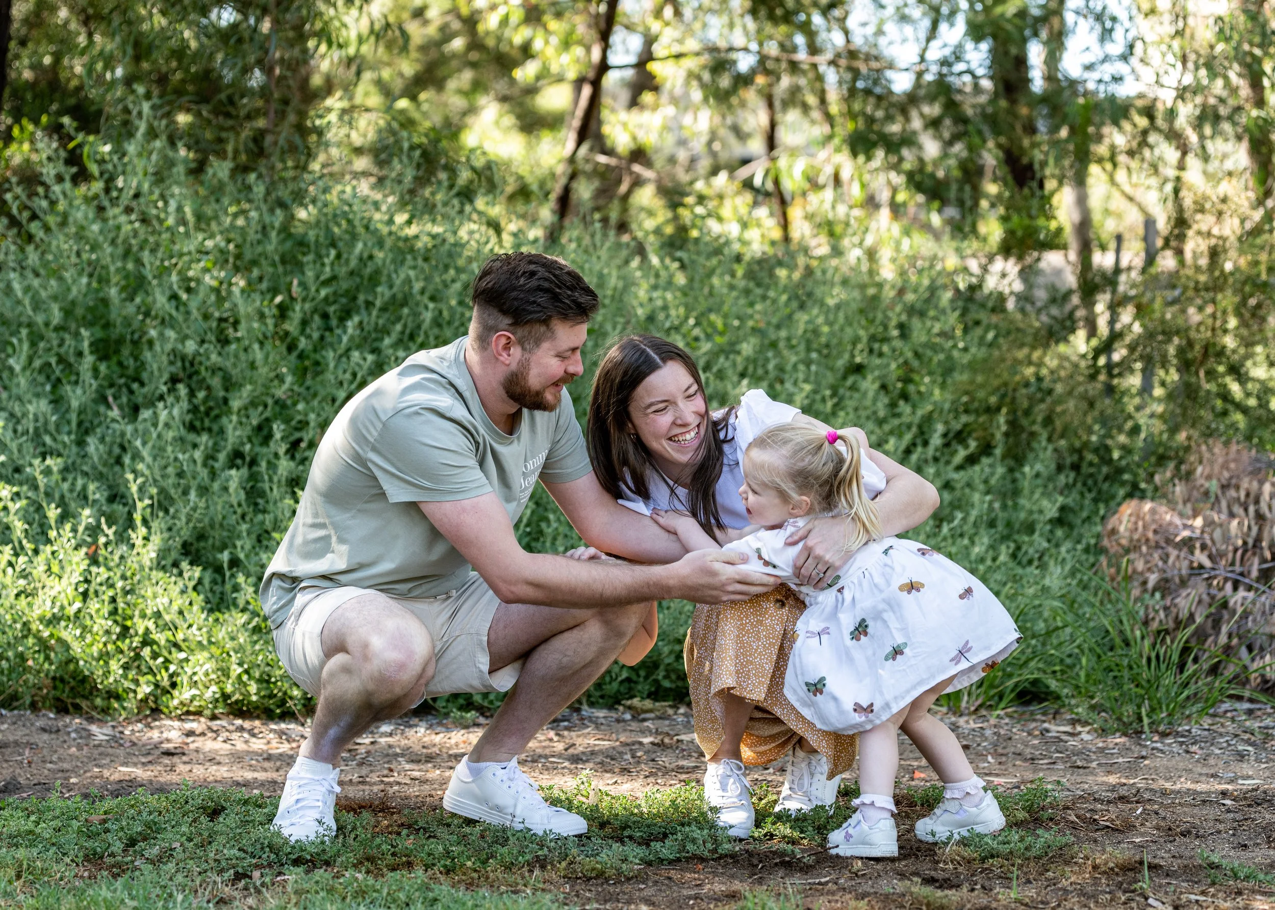A man and woman embrace on a wooden pier with a cloudy sky and water in the background.