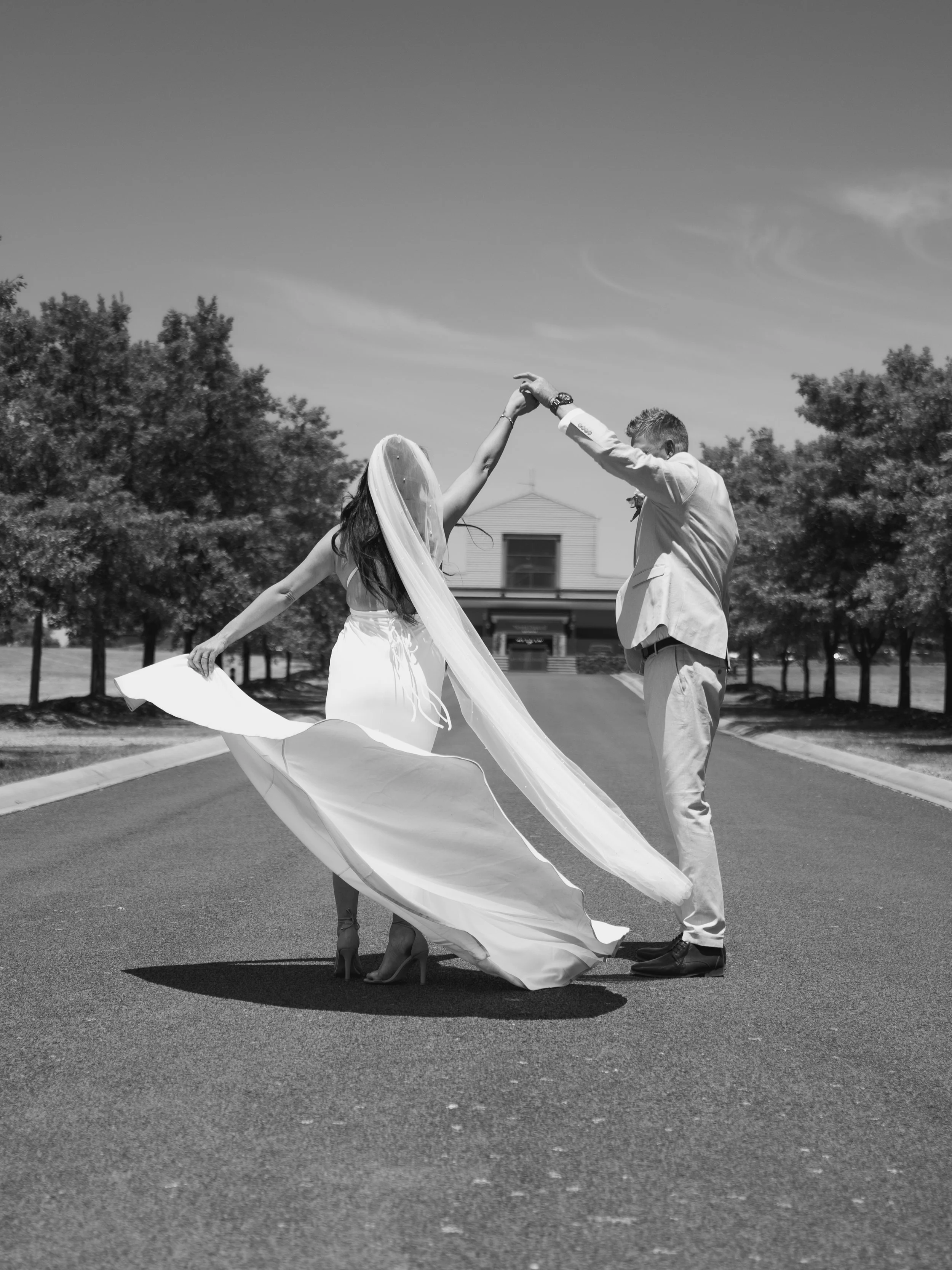 A black-and-white photo of a couple dressed in formal attire descending the steps of parliament house in Melbourne