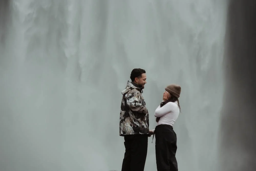 couple getting engaged in front of Skogafoss waterfall