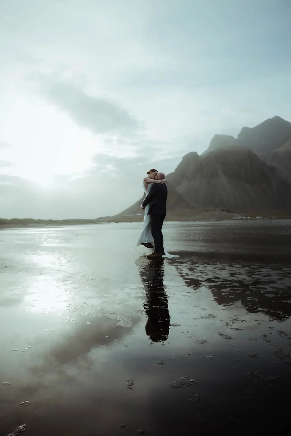 wedding couple sharing their first kiss as a married couple on a black sand beach