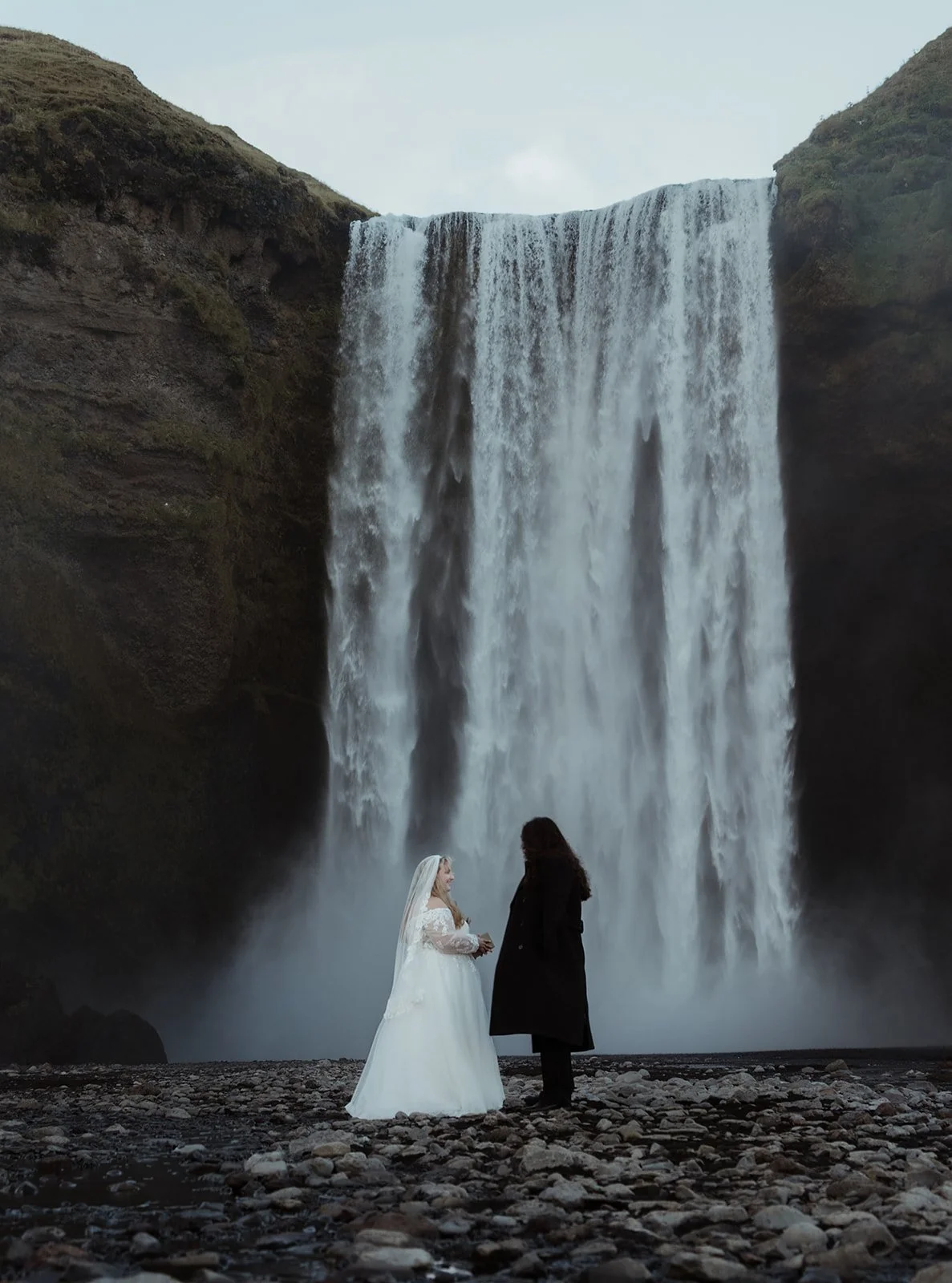 Couple standing together during their intimate vow exchange at Skógafoss
