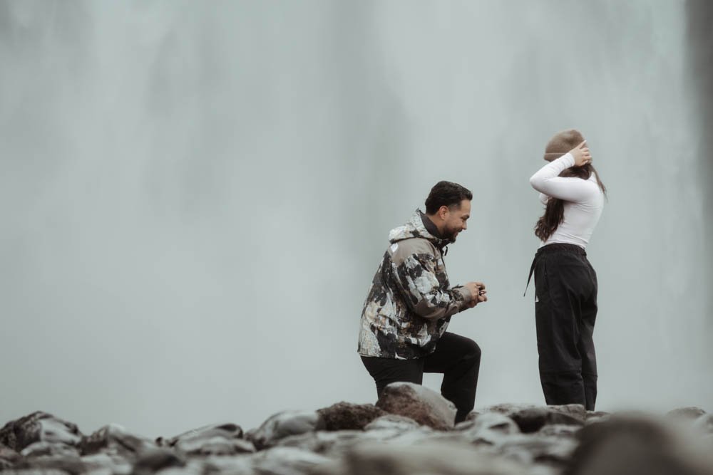 couple getting engaged in front of Skogafoss waterfall