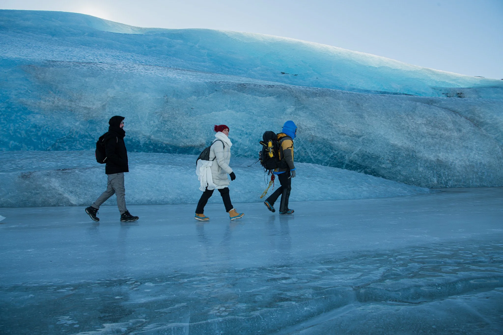 bride and groom walking across frozen glacier lagoon in Southeast Iceland with professional guide