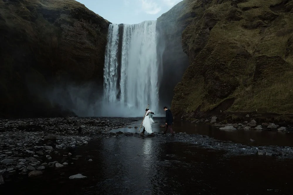 Bride and groom embracing beneath a waterfall during their Iceland elopement in South Iceland
