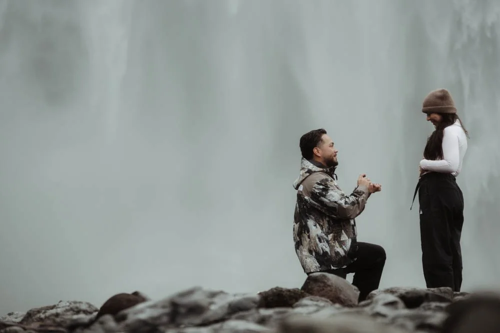 couple getting engaged in front of Skogafoss waterfall