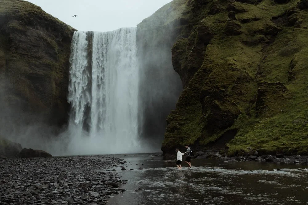 couple getting engaged in front of Skogafoss waterfall
