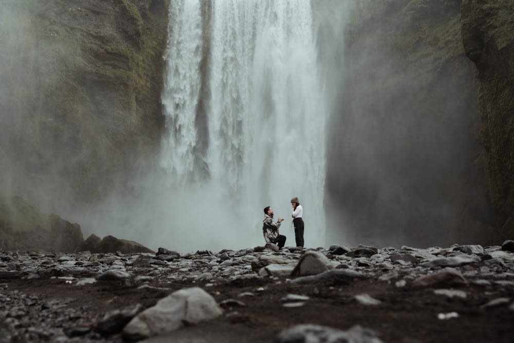 couple getting engaged in front of Skogafoss waterfall