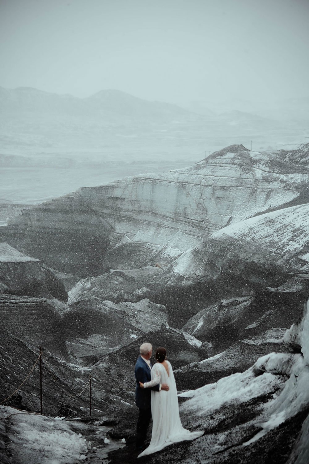 An eloping couple stands together in a snowy glacier landscape during an adventurous winter experience in Iceland.