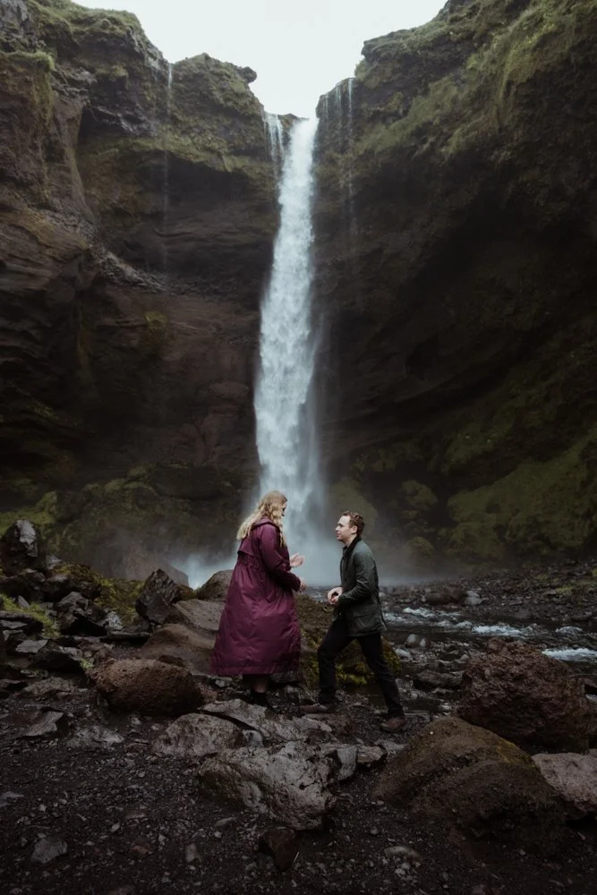William getting down on one knee in front of Kvernufoss waterfall
