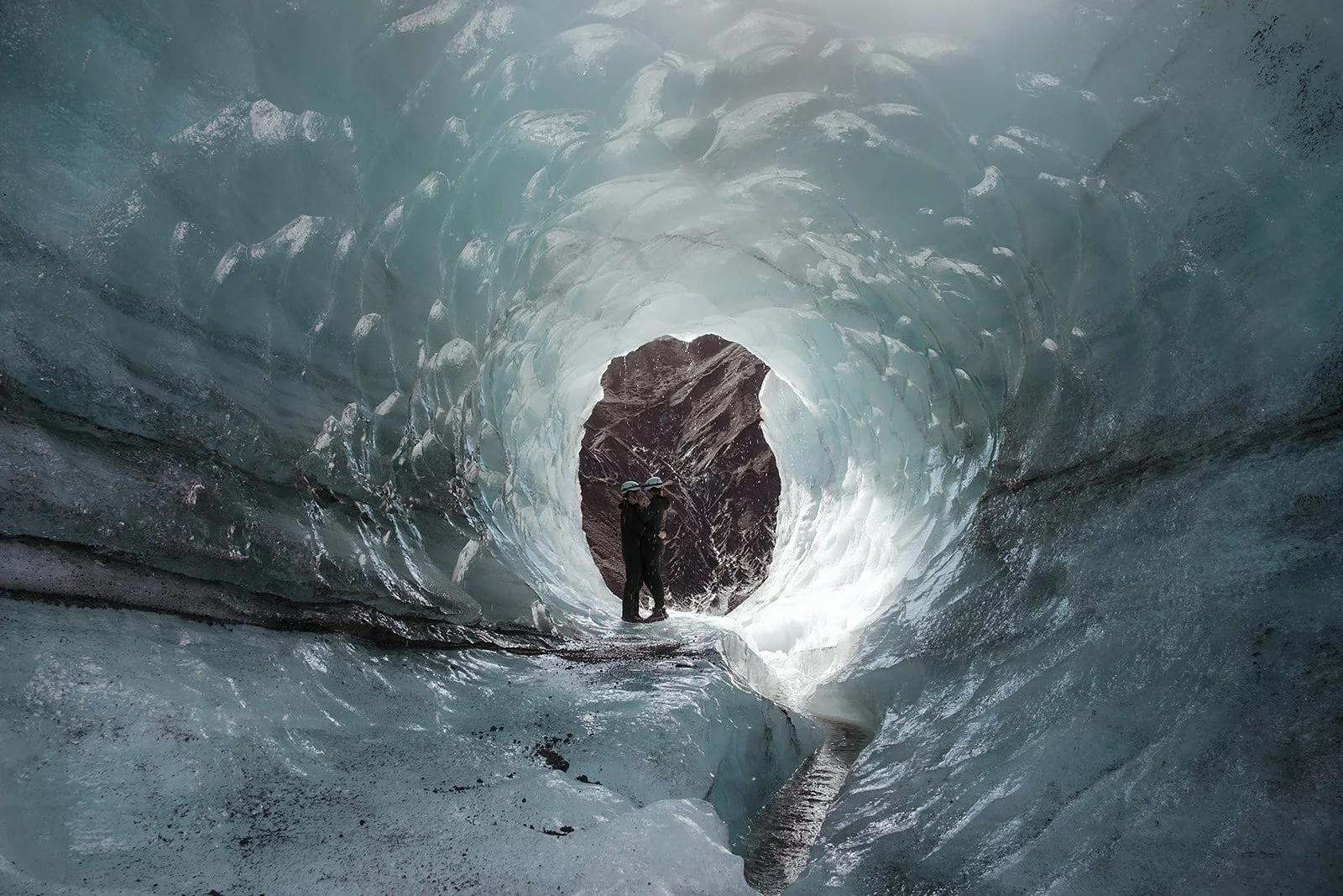 Newly engaged couple inside a naturally formed ice cave at Katla