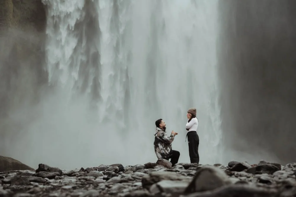 couple getting engaged in front of Skogafoss waterfall