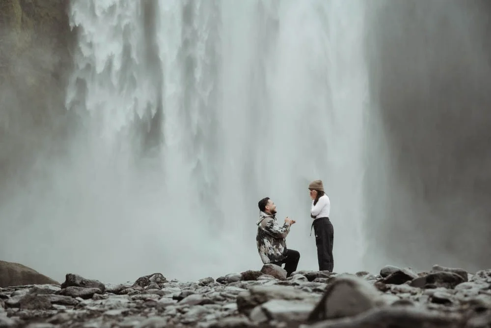 couple getting engaged in front of Skogafoss waterfall