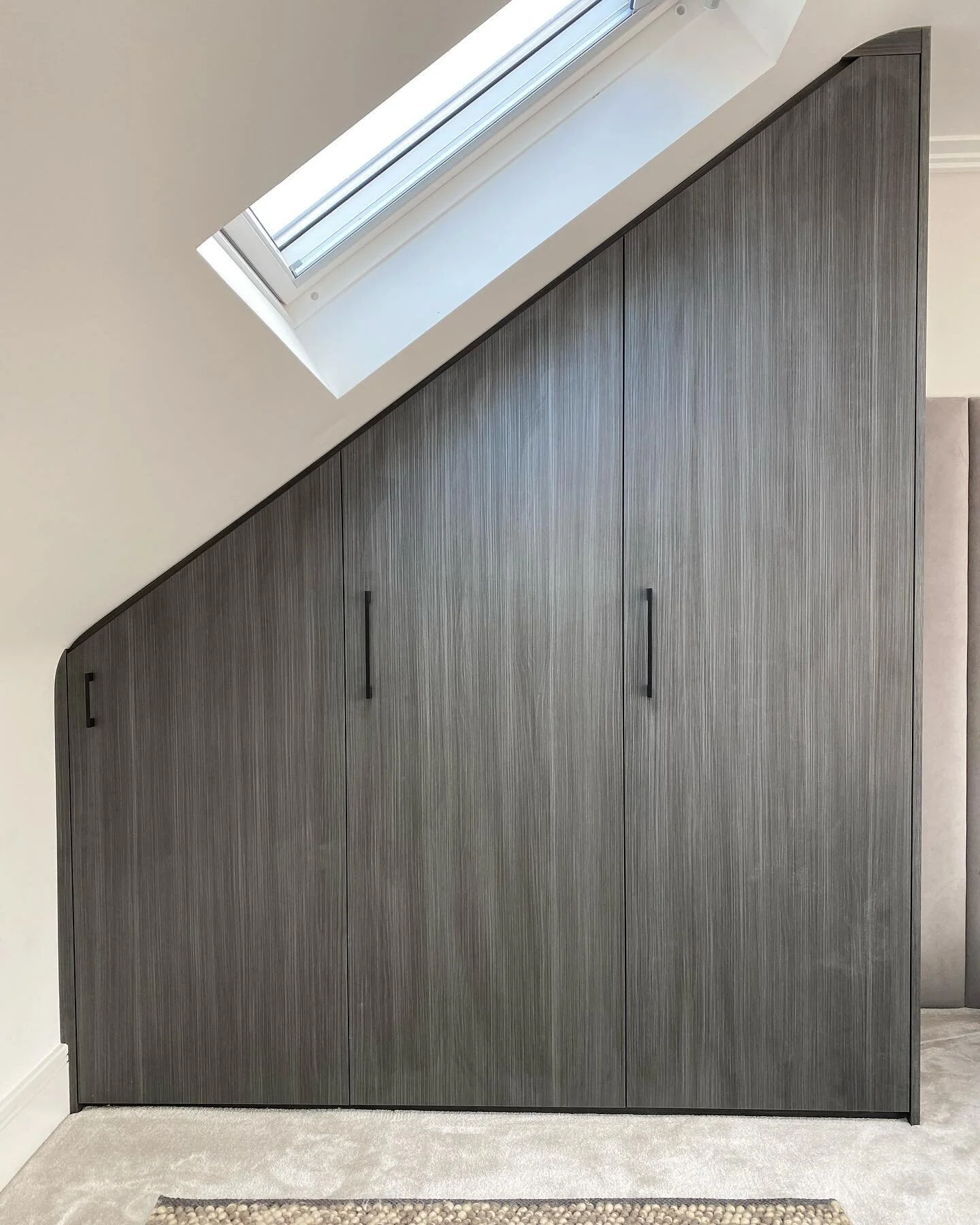 This 3 door angled wardrobe gave the illusion of more space in the eaves by adding a mirror the exact size of the wardrobe on the opposite wall. Maximising all the space with drawers, hanging and shelving as the interior. The doors were on 180° h