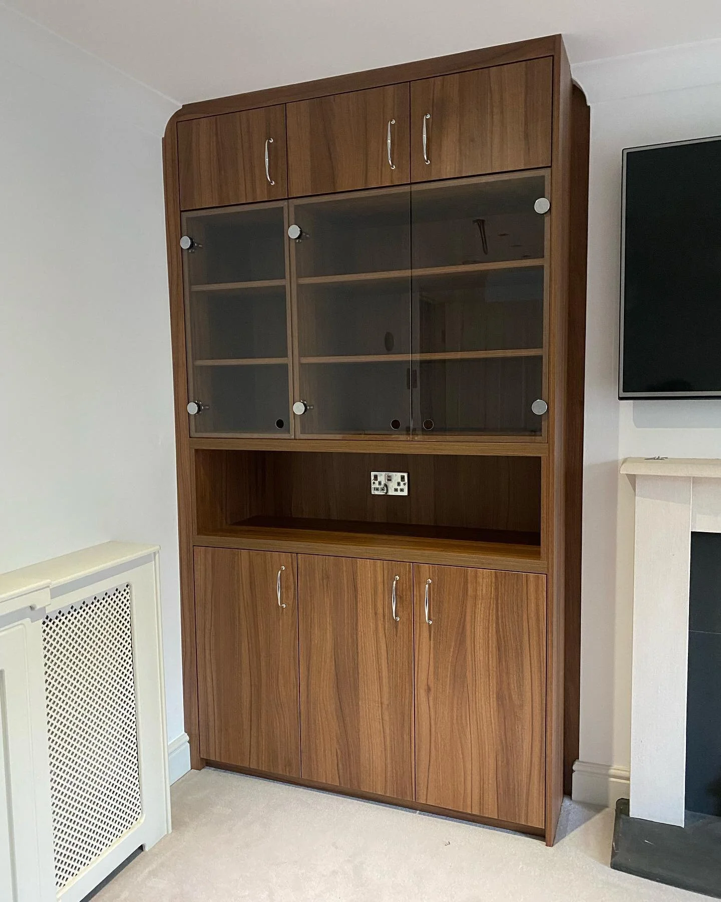 This alcove unit had a glass display cabinet and a cupboard at the bottom to hide the cables for the TV. All finished in Natural Dijon Walnut with chrome handles. #Fitted #FittedFurniture #FittedCabinets #Cabinetry #CabinetryDesign# #Bespoke #Bespoke