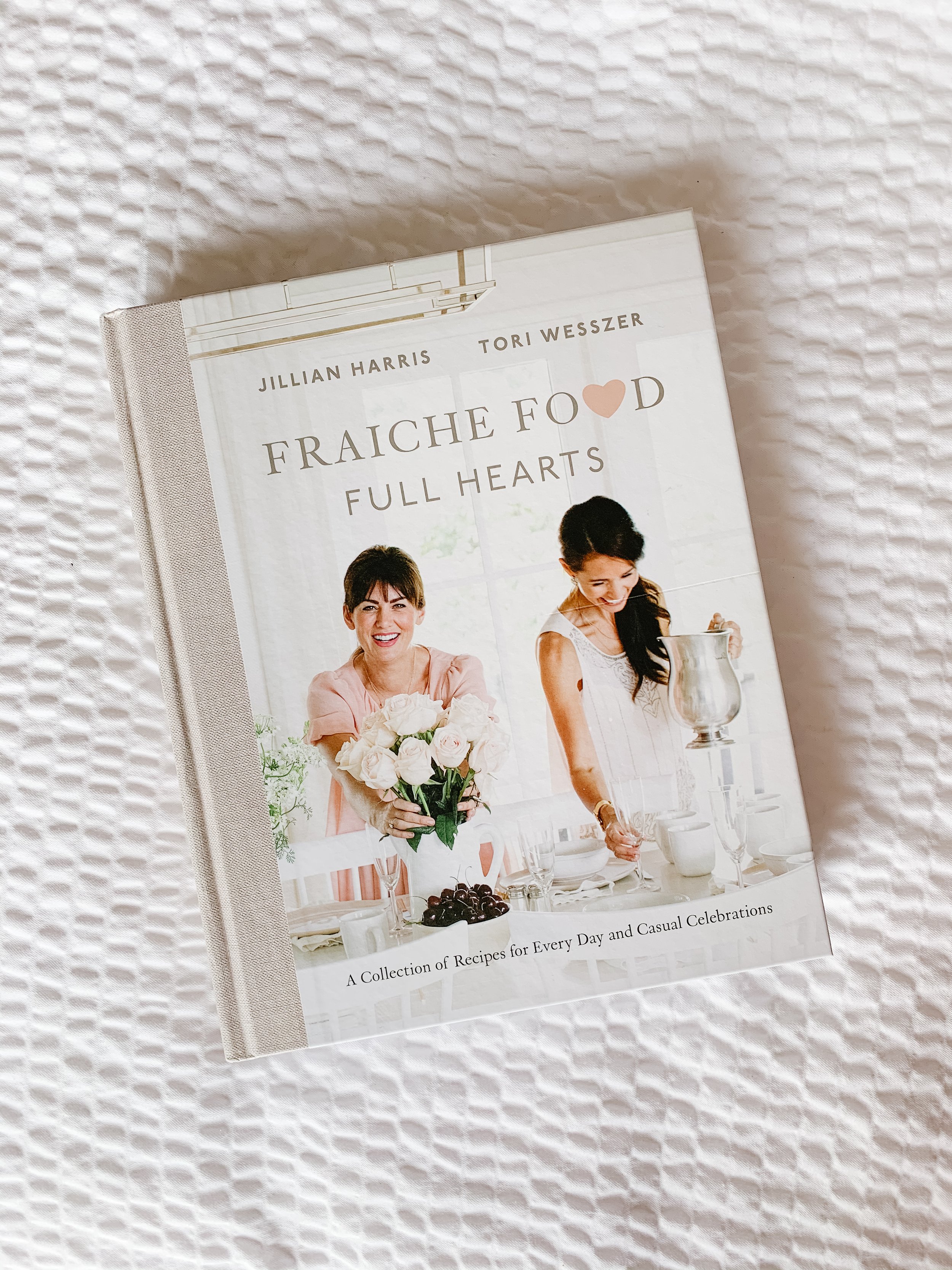 Fraiche Food Full Hearts Cookbook sitting on a bed.