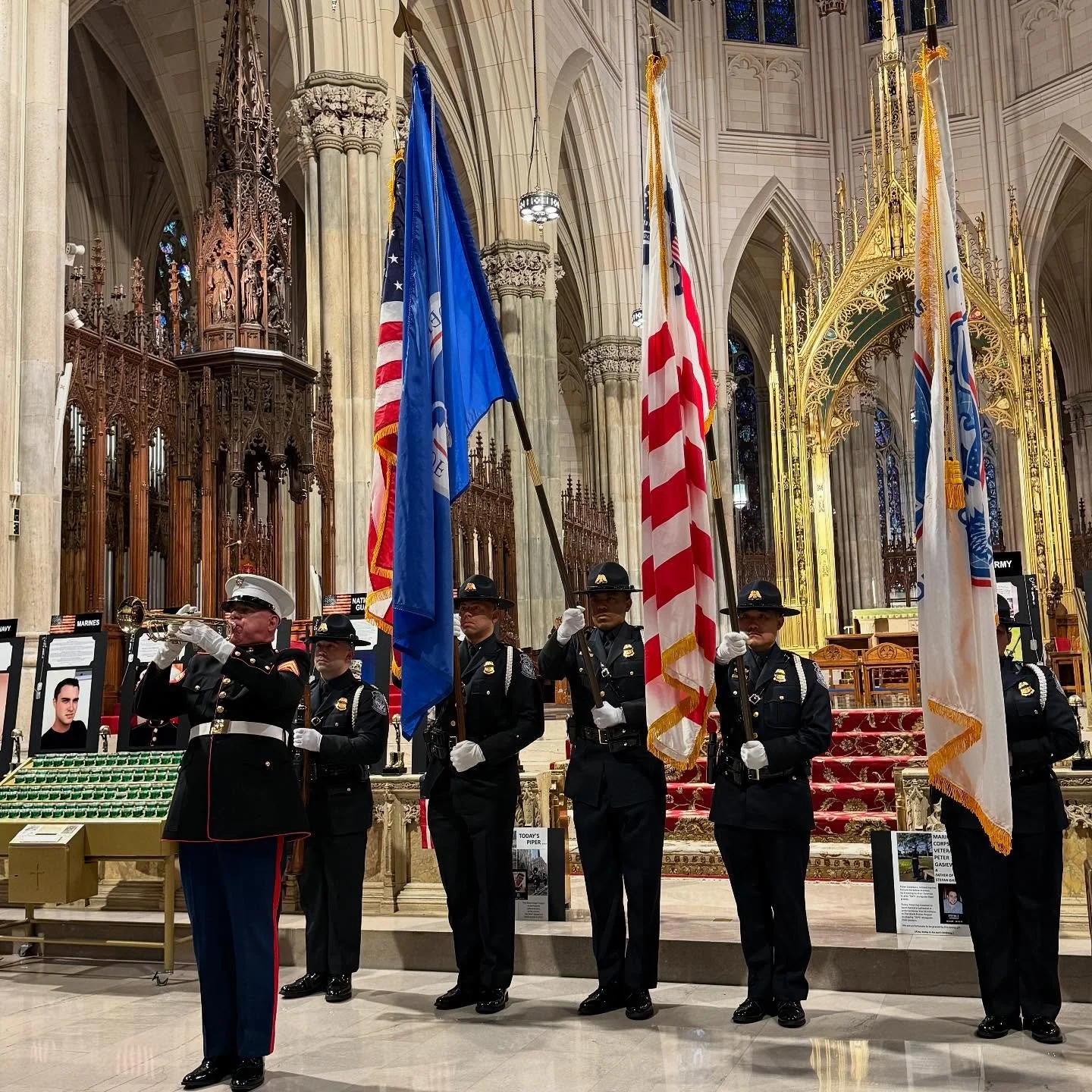 Uniformed honor guard members holding flags inside a grand cathedral with ornate architecture and stained glass windows.