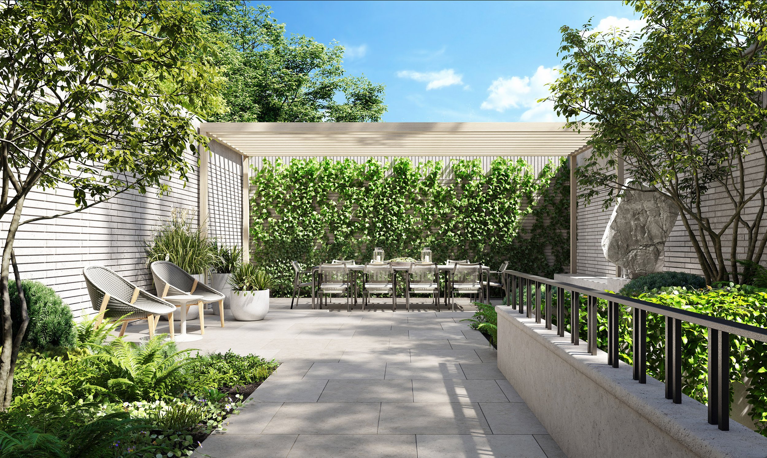 A modern outdoor patio surrounded by lush green plants, trees, and a stone wall with a wooden pergola. There are chairs and tables set for outdoor dining under the pergola, and decorative rocks and potted plants add to the natural ambiance. Blue sky with some clouds is visible overhead.