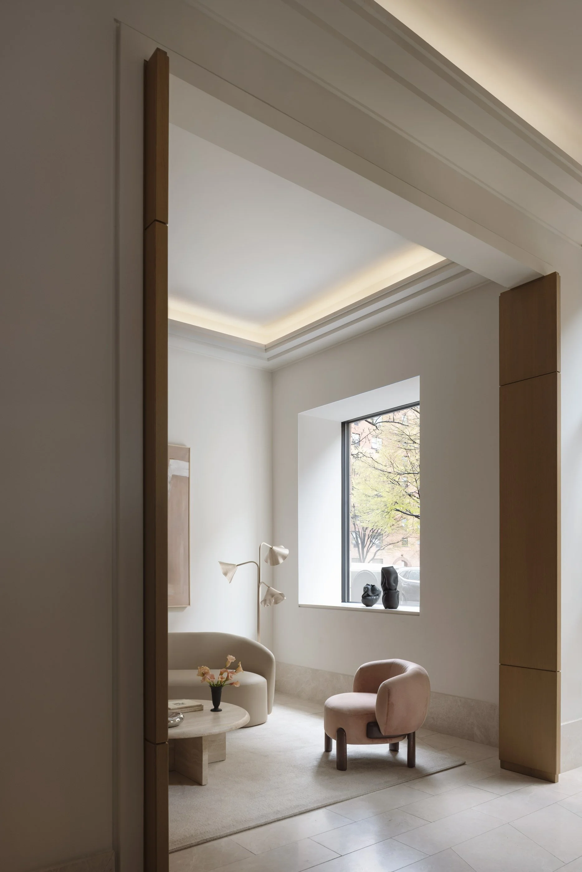 A cozy living room with large window, beige and pastel furniture, modern decor, and simple design.