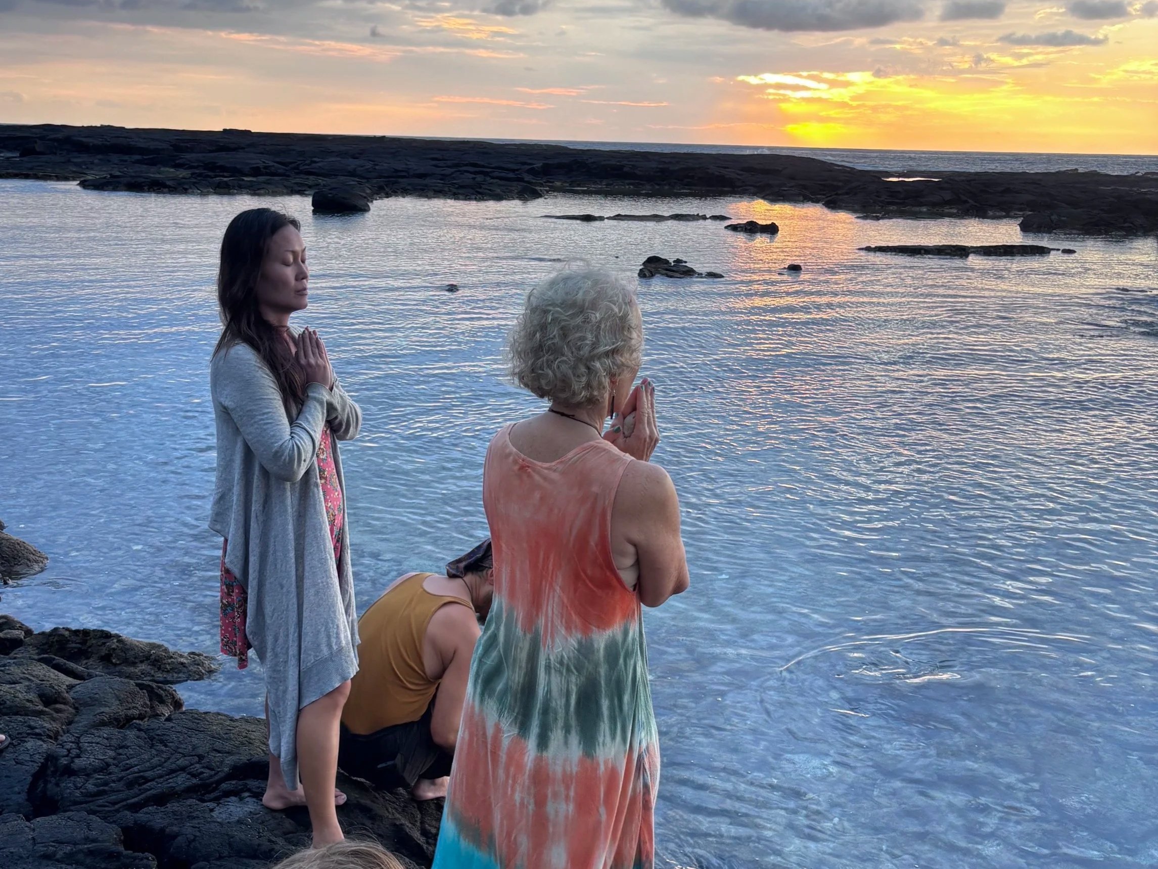 Women in sunset prayer by the ocean at Paliuli women's retreat, Big Island of Hawaiʻi