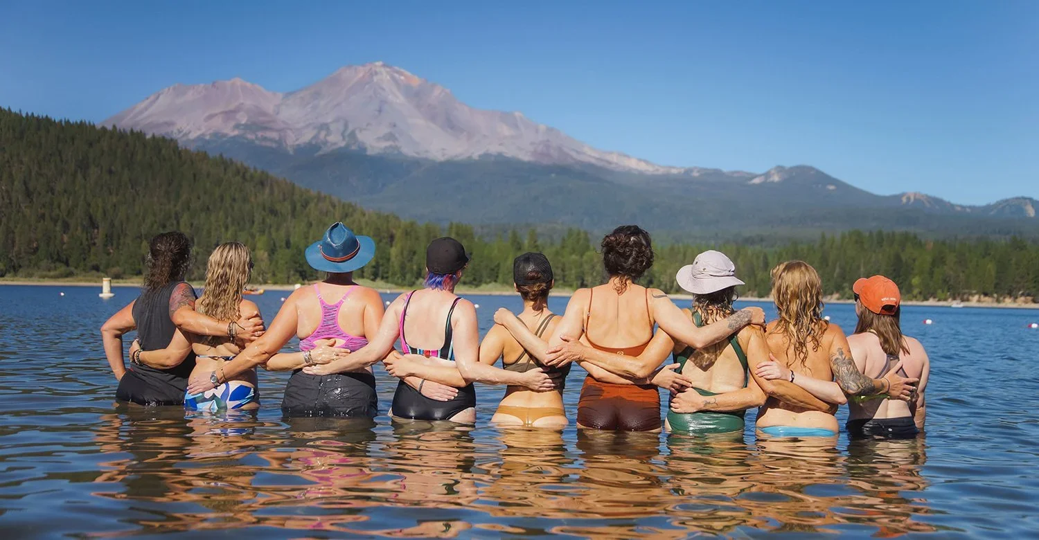 Women embracing in a lake with Mount Shasta rising in the background at a California women's retreat