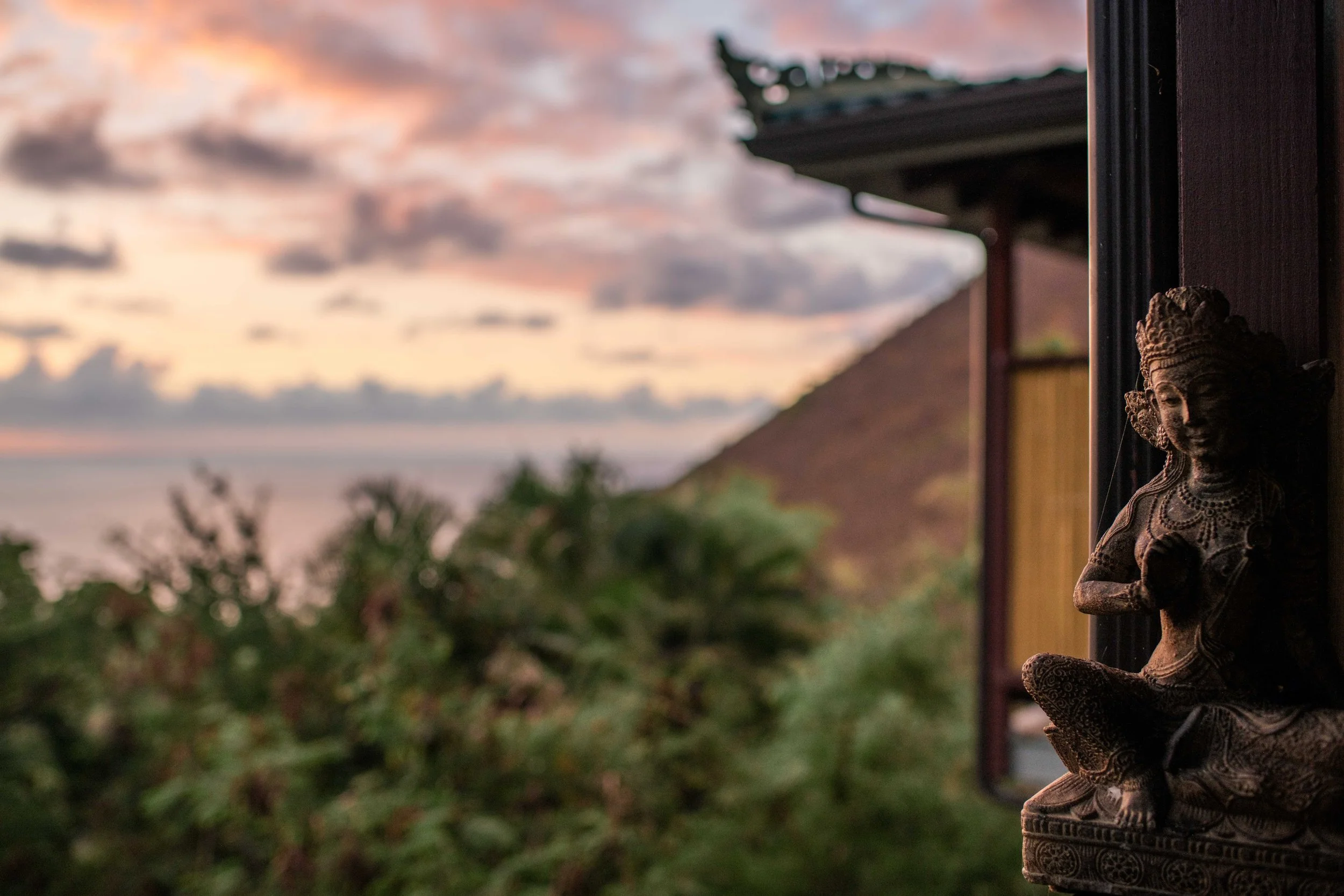 Sunset view over Big Island retreat with ocean horizon and healing sanctuary statue.