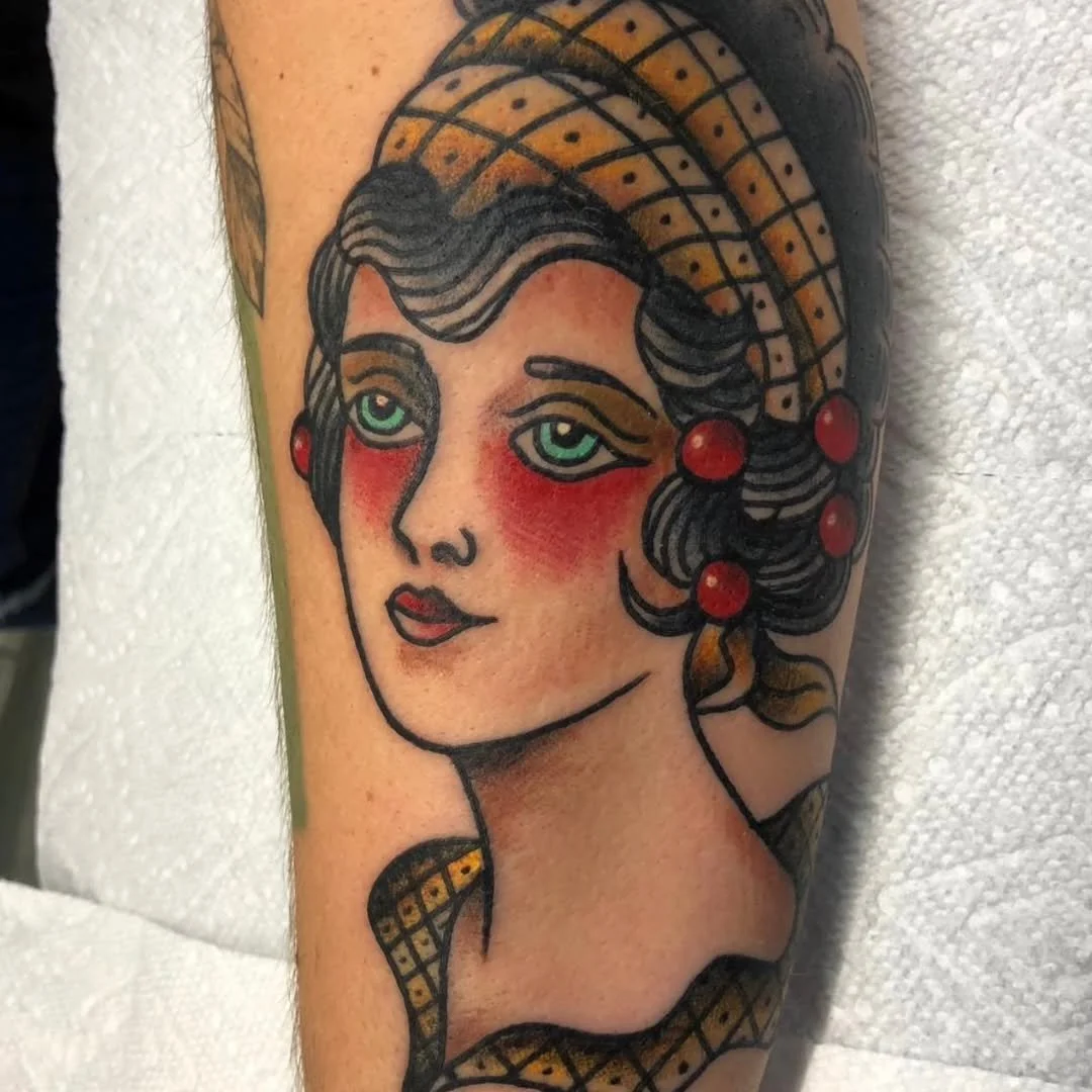 Zack recently tattooed this killer American Traditional portrait of this beautiful woman featuring red and yellow accent colors and piercing green eyes.

If you have a vision for a historical tribute, a mythical creature, or a totally custom blackwor