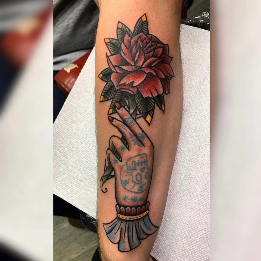 Zack recently worked on this beautiful neo-traditional piece featuring a tattooed hand gracefully holding a stylized rose. This design showcases bold saturation in the flower's petals and unique details like the skull and star tattoos on the hand its