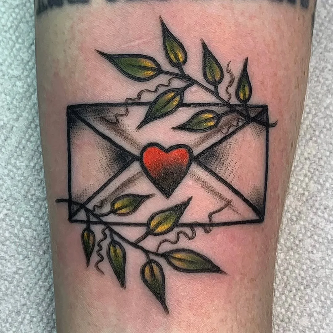 Zack tattooed this beautiful traditional style love letter, sealed with a vibrant red heart and surrounded by gracefully shaded leaves.

Whether you want to commemorate a special message, explore traditional floral designs, or get a custom piece with