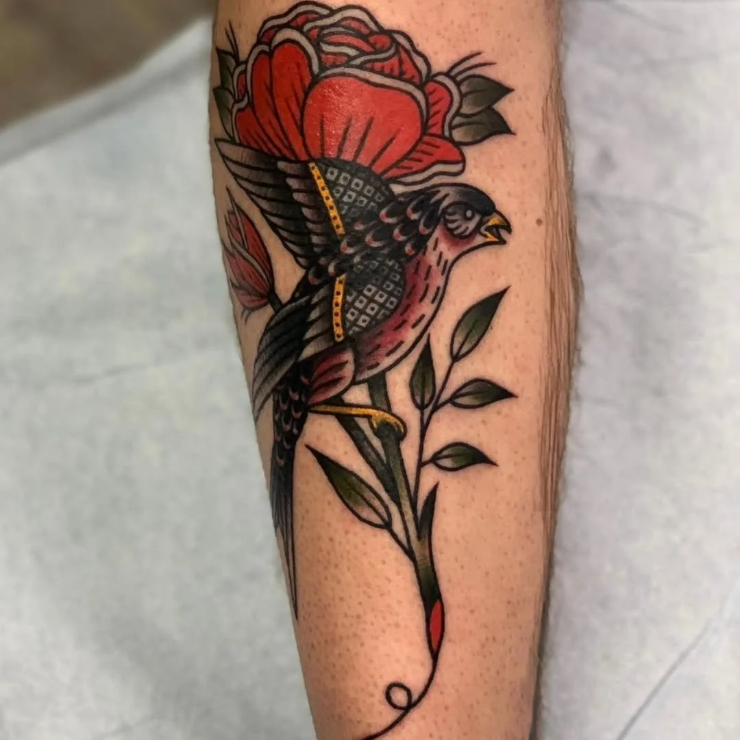 This robin perched on the stem of a red flower is another great piece of traditional ink from Zack! It features bold black outlines paired with the deep, saturated red of the rose petals and delicate yellow accents that make the entire piece stand ou