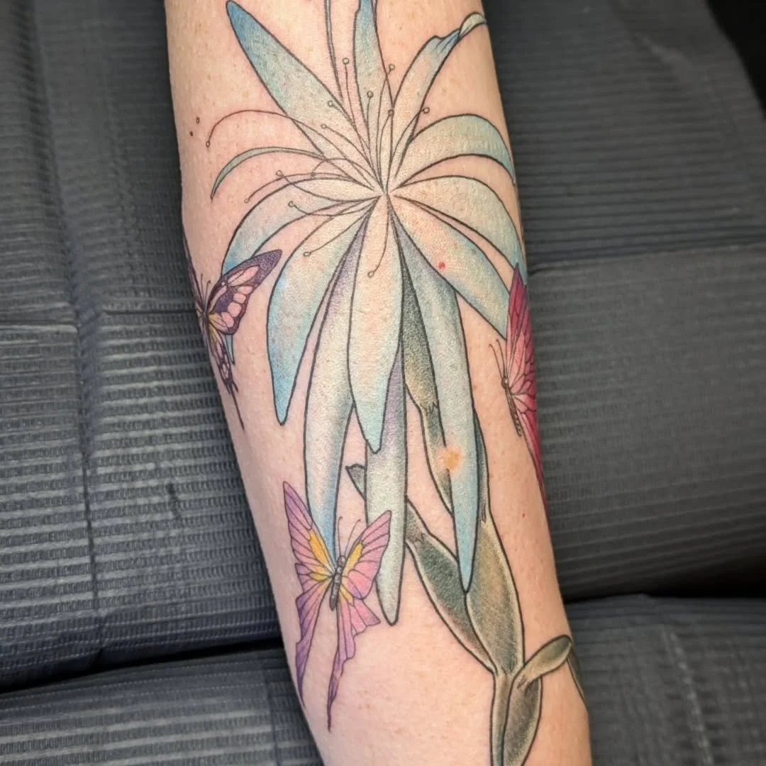 This delicate, stylized spider lily by Rachel is out of this world detailed and delicate in its presentation! Featuring soft light blue tones with subtle white shading across the petals, the design is beautifully decorated with a flutter of similarly
