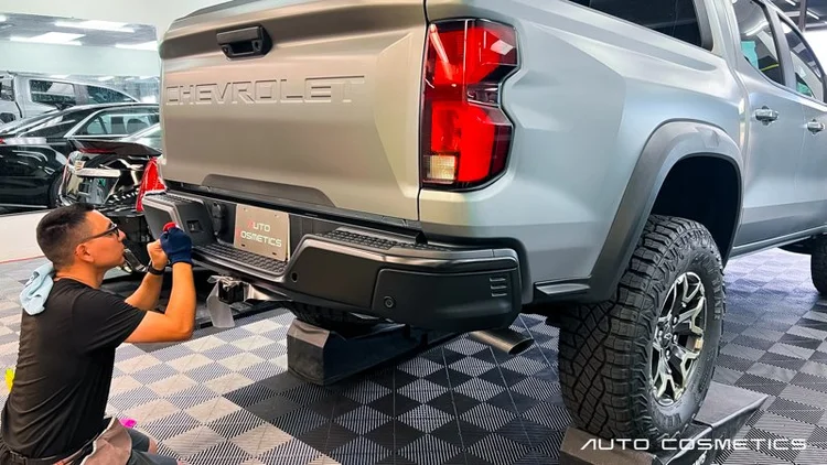 Installer applying matte silver paint protection film to a Chevrolet Colorado at Auto Cosmetics in Chandler, Arizona