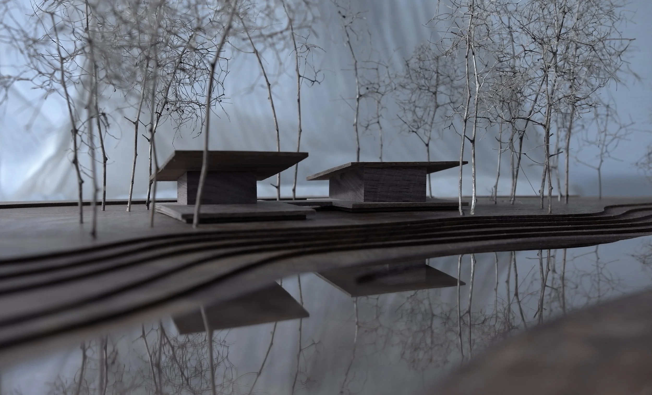 Modello in scala di una futura area residenziale con due edifici architettonici e alberi fogli liberi.