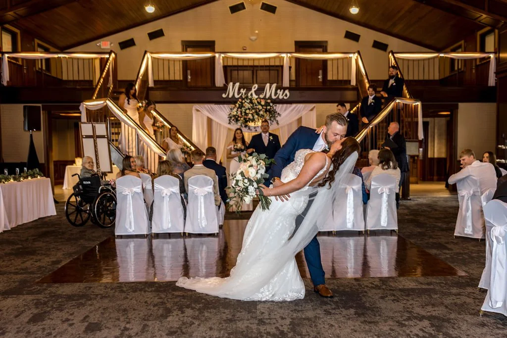 A bride and groom share a kiss during their wedding reception in a decorated venue with a 