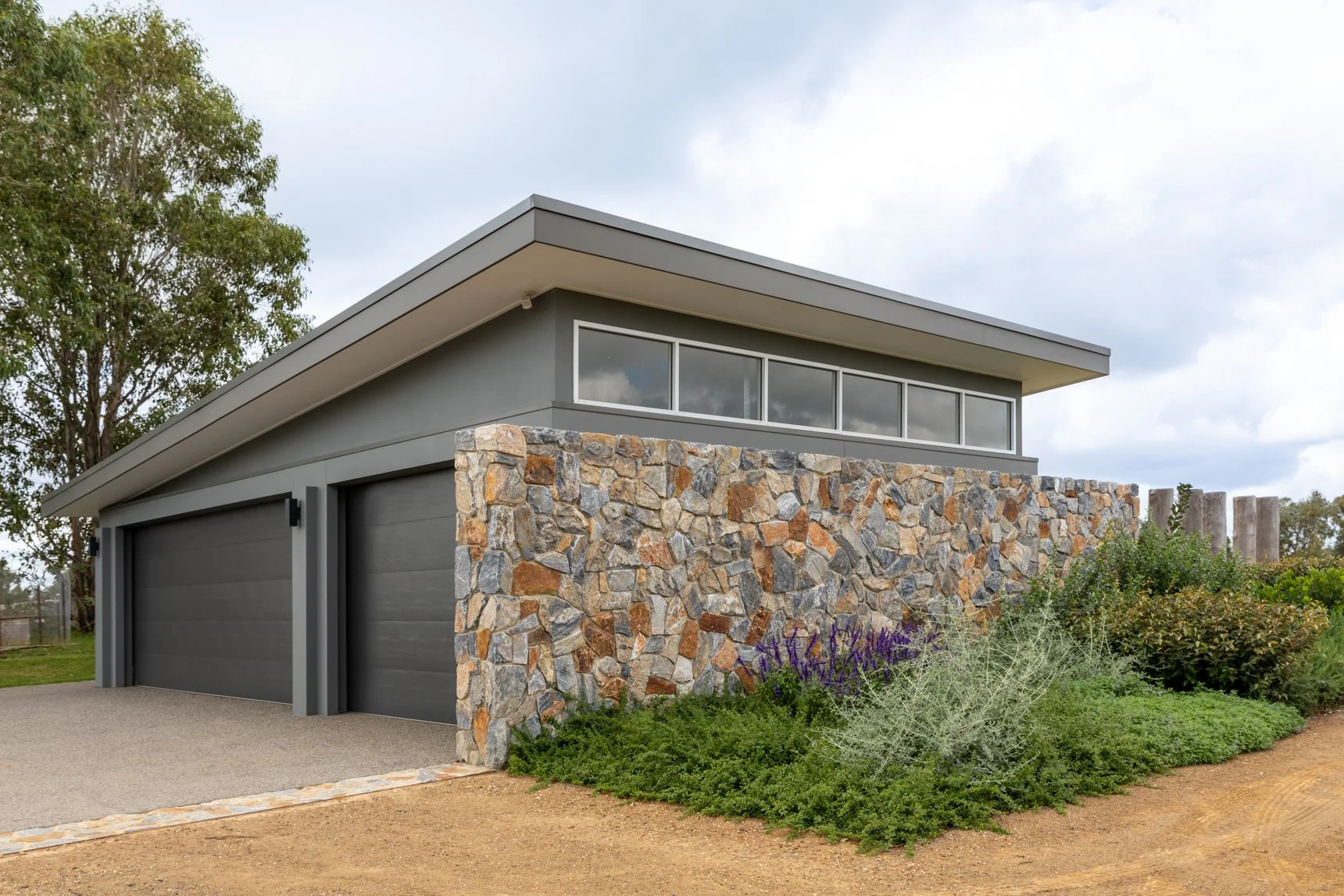 Custom home builders Newcastle project with stone wall and modern garage.
