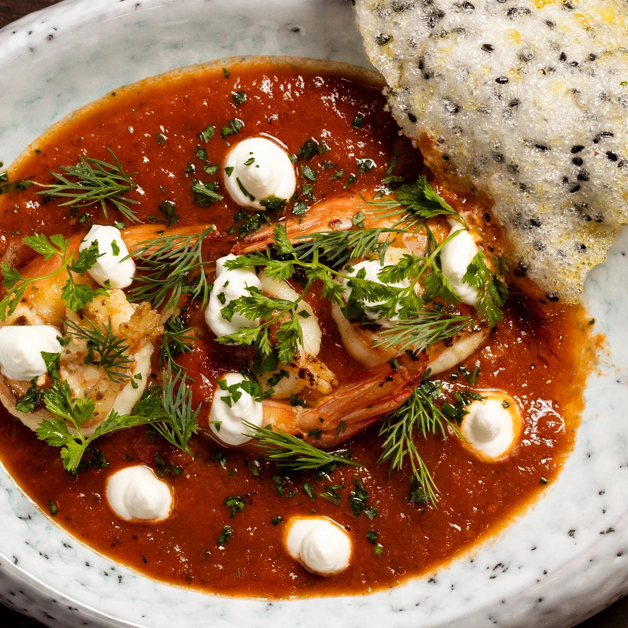Shrimp in tomato sauce garnished with cilantro and dill, served with a rice cake or cracker.