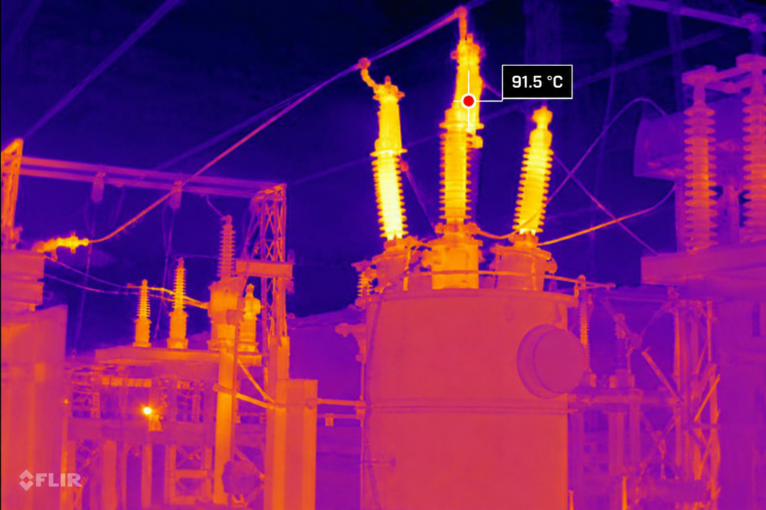 Infrared thermal image of an electrical substation with transformers and power lines, featuring a highlighted area with a temperature of 91.5°C.