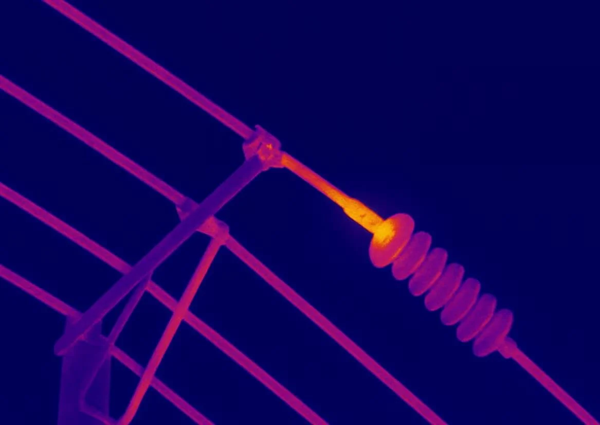 Infrared image of an electrical power line insulator and a part of the supporting structure against a dark sky.
