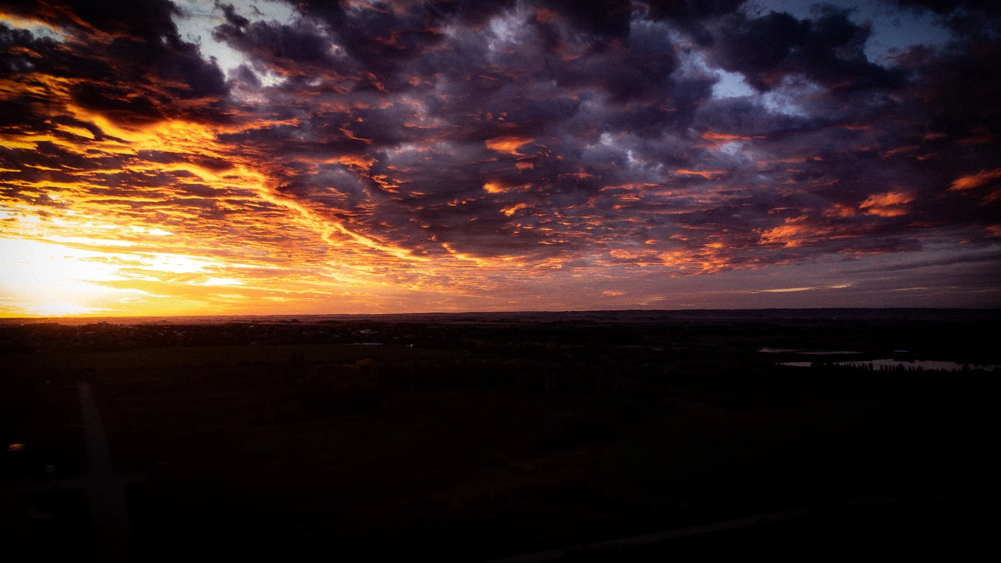 A vibrant sunset with orange and purple clouds over a wide open landscape Winnipeg Manitoba.