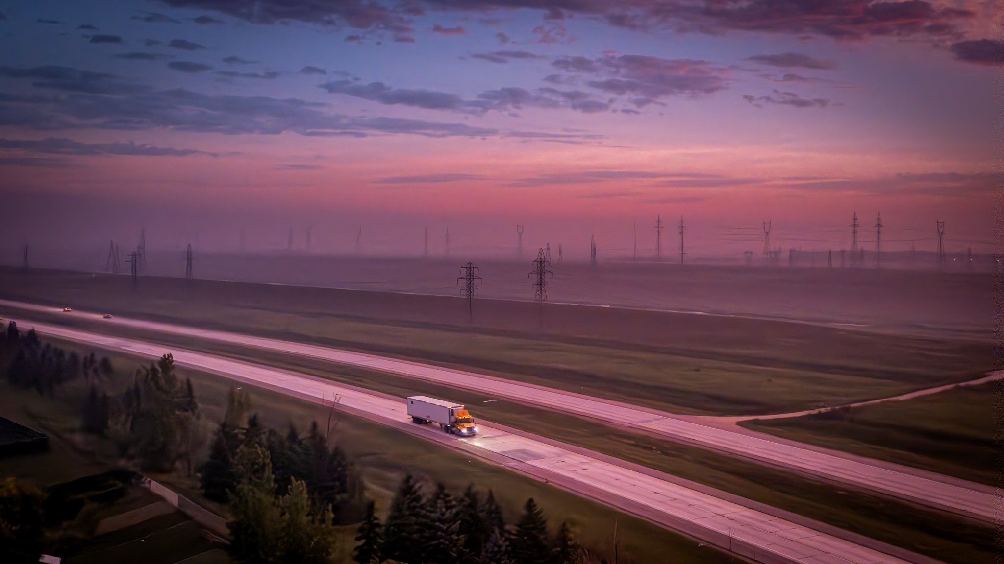 A semi-truck driving on an empty highway at dusk with power lines and pylons in the background and a colorful sky with purple and pink clouds Winnipeg Manitoba.